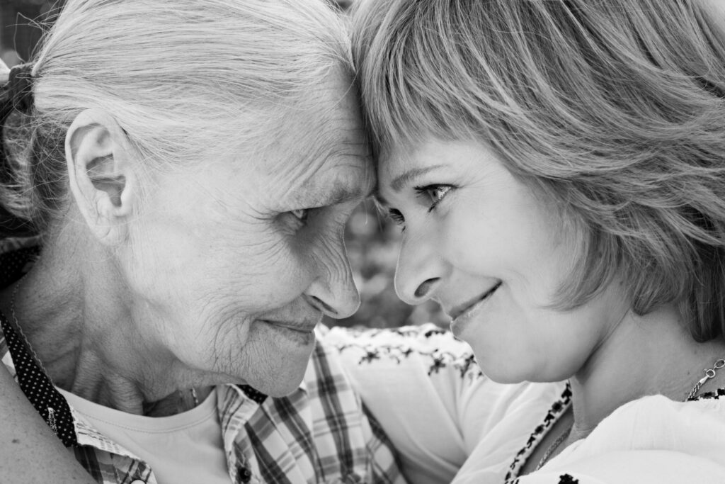 Middle-aged woman in social isolationhugging her mother in nature. The real emotions of happiness. Mothers Day. Black and white photo.
