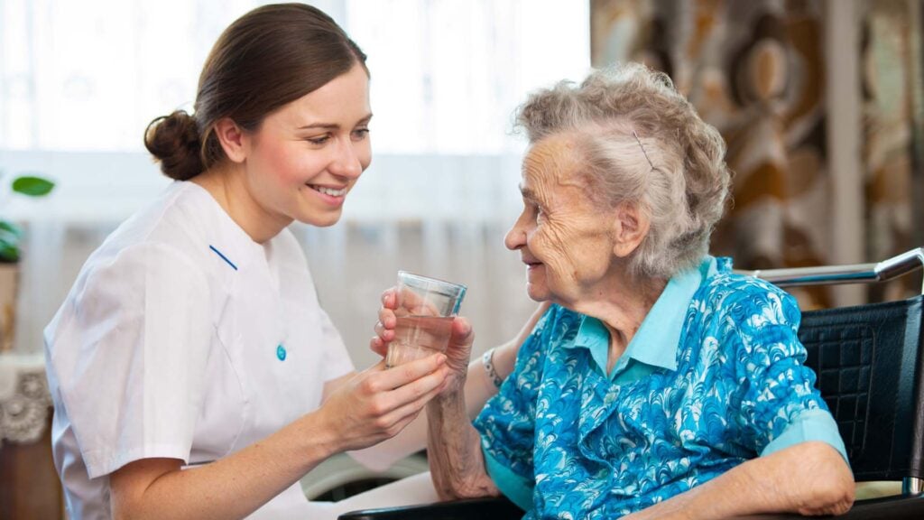 caregiver giving water to client during home care in-home services