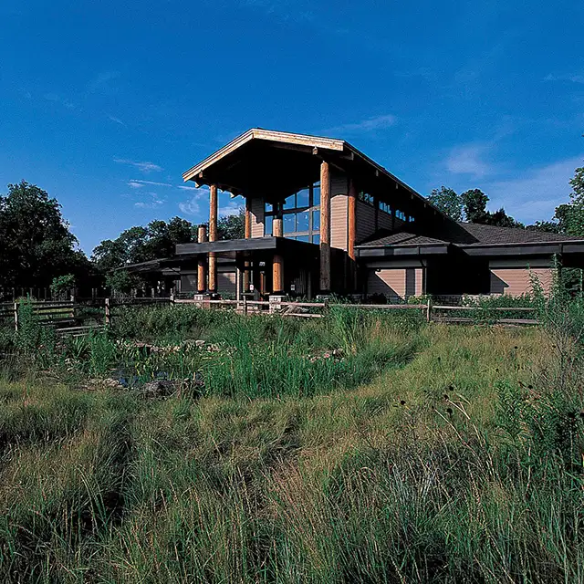 view of the Fontenelle Forest Nature Center building with blue sky above and native plants growing in front of it